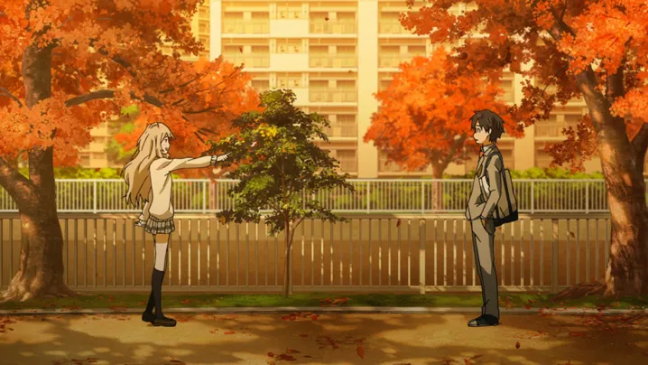 A girl with long blonde hair points at a boy standing in front of her on a path lined with autumn trees.